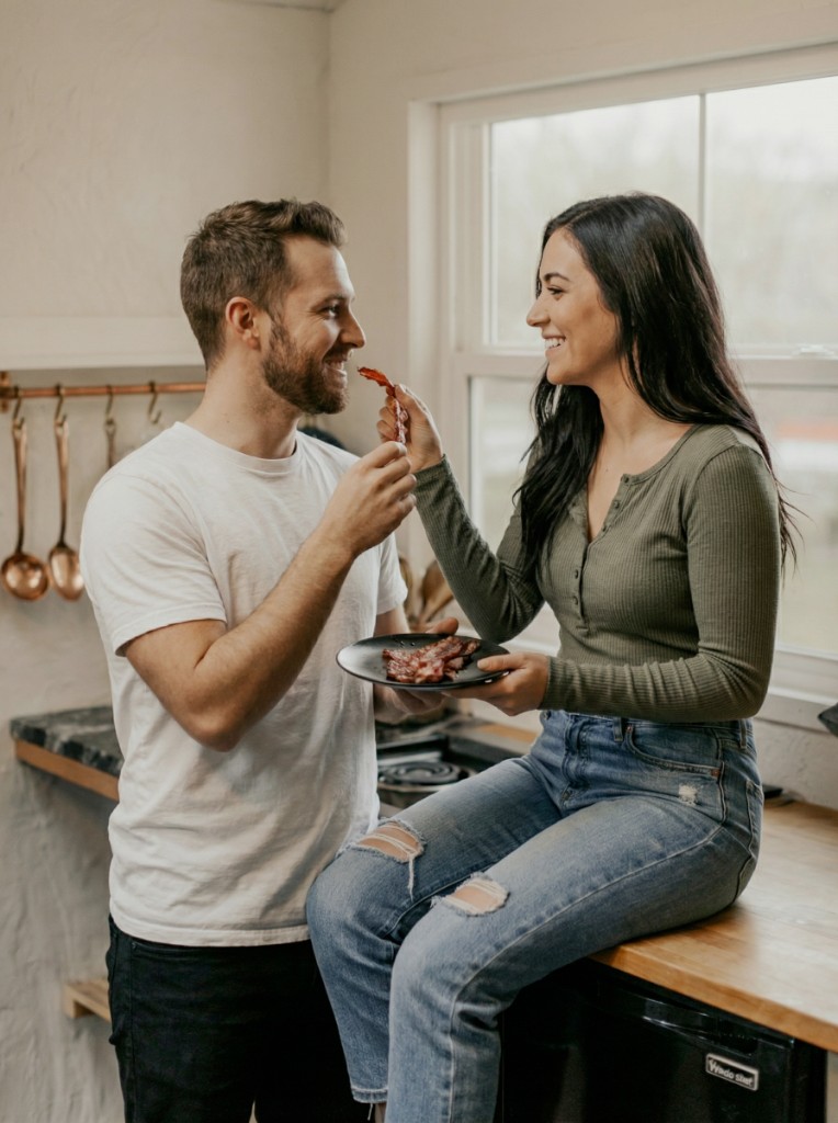 A smiling couple in a bright kitchen sharing a relaxed moment together at home